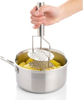 une casserole remplie de patates avec un presse purée et une main l’actionnant