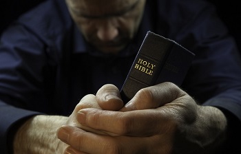 Un homme en prière tient sa Bible
