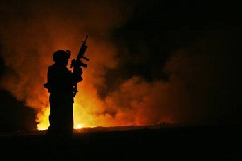 un soldat armé devant le feu d’une armée déchaînée